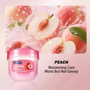 Close-up detail of ADMD peach moisturizing lip balm jar with a fresh peach backdrop