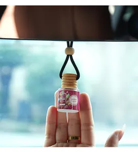 Gros plan d'un flacon d'aromathérapie FORMBO pour voiture tenu à la main en détail