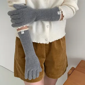 Detail view of grey long ribbed knit gloves featuring a contrast white trim and logo tag