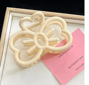 Gros plan d'une pince à cheveux en forme de cœur blanc crème sur fond minimaliste
