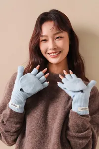 Close-up of blue 100% wool flip-top knitted fingerless gloves worn by a smiling model.