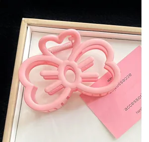 Gros plan d'une pince à cheveux rose mat en forme de cœur évidé.