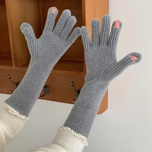 Detailed view of grey knitted long arm warmer gloves with elegant white ruffle trim on hands