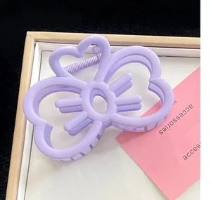 Gros plan d'une pince à cheveux violette en forme de cœur avec un motif papillon élégant.