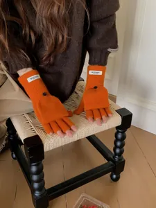 Detailed view of bright orange wool convertible fingerless mittens with button closure