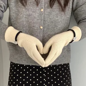 Close-up of cream ribbed knit gloves with heart gesture showing soft texture