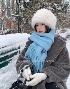 Detailed shot of a model wearing a light blue wool scarf and white faux fur hat in snow
