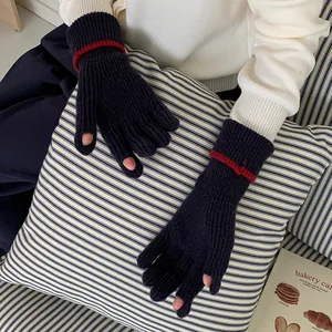 Detail view of navy blue knitted winter gloves with red stripes and finger openings.