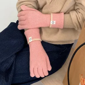 Detailed view of pink knitted gloves with a stylish patch label for winter warmth.