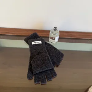 Close-up of charcoal grey 100% wool convertible fingerless mittens with button.