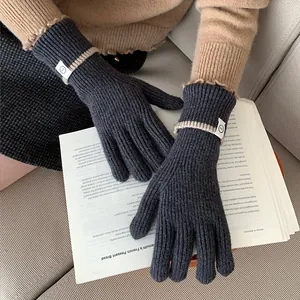 Close-up view of dark grey knitted winter gloves featuring a stylish white label detail