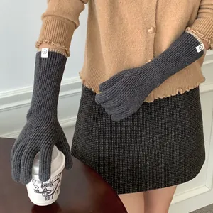 Premium dark grey knitted winter gloves for women shown in a cozy lifestyle setting