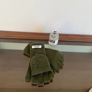 Close-up of dark green 100% wool flip-top knit gloves showing soft texture and tag.