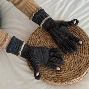 Pair of dark grey ribbed knit gloves with contrast beige stripe on woven mat background