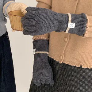 Close-up of grey knitted gloves with a decorative white tag and contrast ribbing