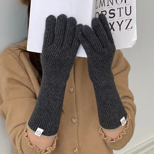 Detail view of women's warm grey knitted gloves with minimalist white labels for winter
