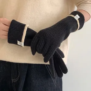 Close-up of black knit gloves with contrast stripes and logo label for winter