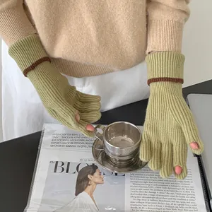 Detail of pale green knitted fingerless gloves with a contrast brown wrist stripe.