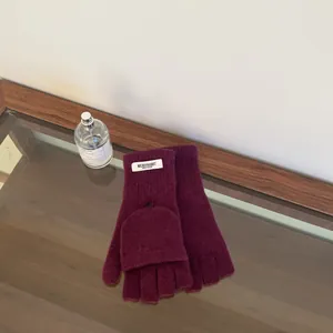Top down view of purple 100% wool convertible mittens on a wooden table surface