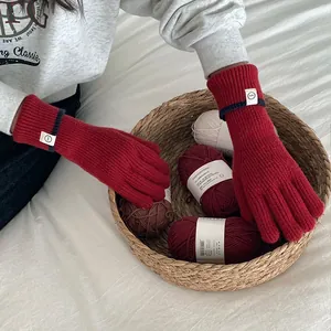 Close-up view of red knitted gloves with patch used in a cozy winter lifestyle setting