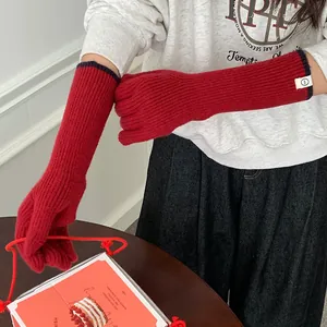 Detailed view of red knitted winter gloves with contrast trim and a stylish white patch