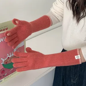 Detail view of pink long knitted winter gloves with contrasting trim and patch