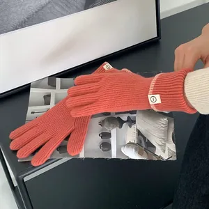Close-up of orange knitted winter gloves with ribbed texture and wrist label