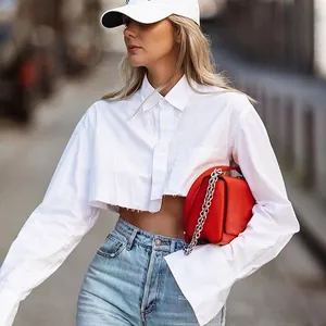 Detalle de camisa blanca corta de manga larga con dobladillo deshilachado y cuello