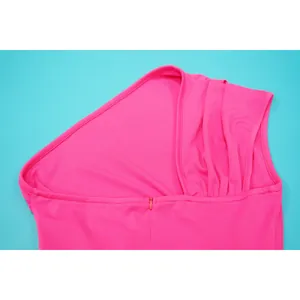 Detail of a bright pink one-shoulder dress featuring pleated shoulder and hidden zipper.