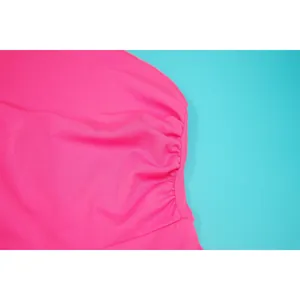 Macro view showing the ruched waist and stitching detail of a vibrant pink summer dress