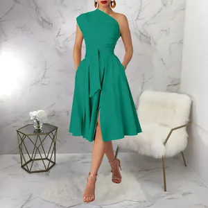 Detail view of emerald green one-shoulder dress featuring a cinched waist and pleated skirt