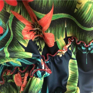 Macro detail of tropical leaf print fabric featuring ruffled edge with red overlock stitching