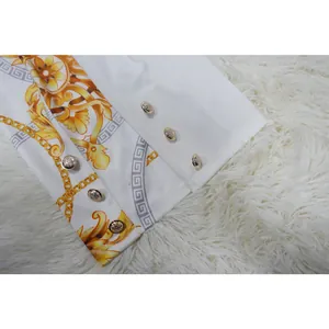 Détail de la manche d'une veste blanche avec imprimé baroque doré et boutons en métal