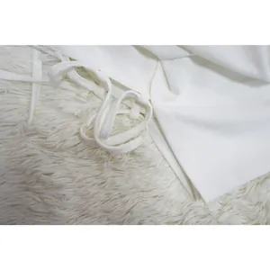 Macro-weergave van witte blazerstof met elegante strikbandjes en fijn stikselwerk