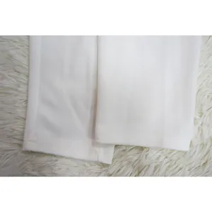 Gedetailleerde close-up van de precieze dubbelgestikte zoom van een witte modieuze broek