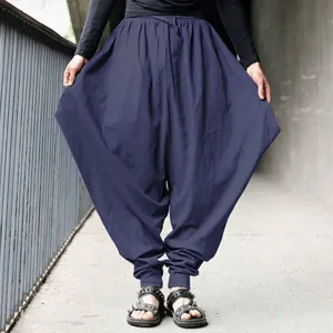 Macro detail view of men's loose navy blue harem pants with a lantern silhouette style