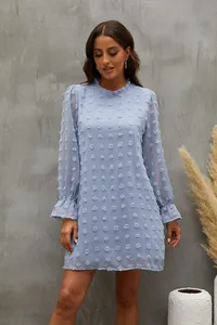 Dettaglio di un abito in chiffon azzurro a maniche lunghe con pompon testurizzati