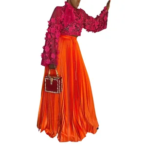 Elegant bright orange pleated silk-like maxi skirt paired with pink lace floral blouse