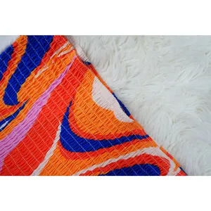 Detailed close-up showing the smocked elastic texture and vibrant abstract print of the dress
