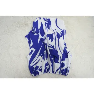 Detailed view of women's sleeveless blue and white floral print top on white rug