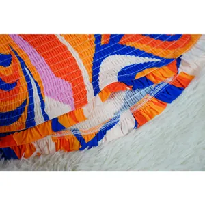 Close-up detail of the elastic smocking and ruffled hem on a vibrant printed dress