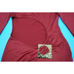 Detailansicht eines eleganten burgunderfarbenen Kleides mit Schlitz und Goldschnalle
