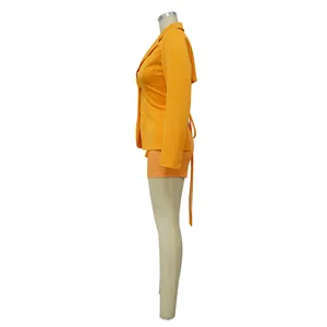 Zijaanzicht van een levendige oranje tweedelige blazer- en shortset voor trendy dames.
