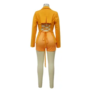 Achteraanzicht van oranje cropped blazer met vetersluiting en bijpassende short