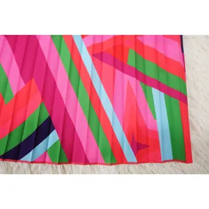 Detail view showing vibrant geometric print and fine pleated texture on summer beach dress