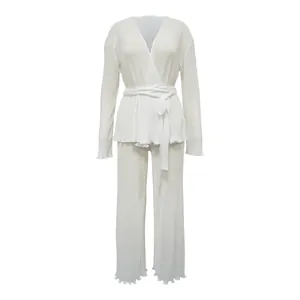 Close-up of a white two-piece pleated lounge set with a wrap-style top and matching wide-leg trousers