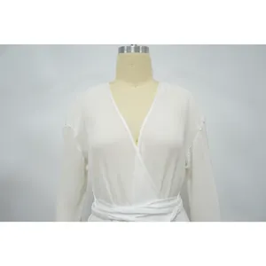 Close-up detail showing the fine pleated texture of a white long-sleeved wrap dress