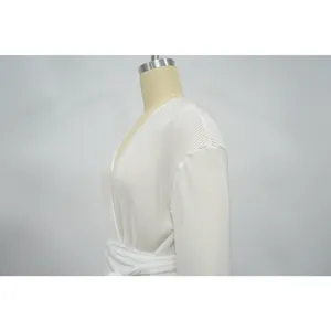 Detailed close-up of white plissé long sleeve top with fine vertical pleat texture