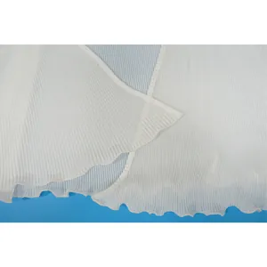 Macro view of pleated white fabric showing texture and hemline details on the garment