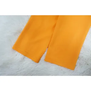 Detailopname van de mouwmanchetten van een feloranje blazer met zeer strakke stiksels